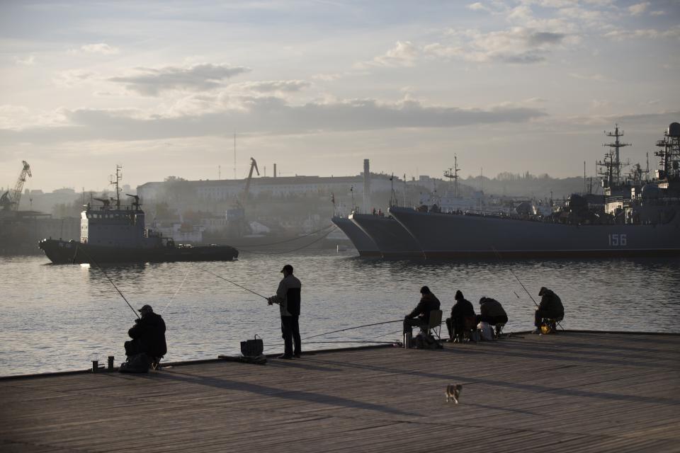 FILE - Local fishermen try to catch fish in front of Russia Navy ships in Sevastopol, Crimea, Oct. 27, 2014. Successful Ukrainian drone and missile strikes have provided a major morale boost for Kyiv at a time when its undermanned and under-gunned forces are facing Russian attacks along the more than 1,000-kilometer front line. Challenging Russia’s naval superiority also has helped create more favorable conditions for Ukrainian grain exports and other shipments from the country’s Black Sea ports. (AP Photo/File)