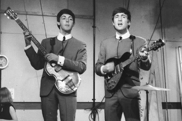 <p>David Redfern/Redferns</p> John Lennon in 1963 (playing a 1958 Rickenbacker 325 guitar — not the one being put up for auction).