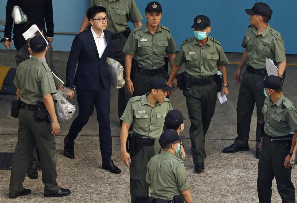 FILE - Hong Kong Activist Edward Leung, second left, is escorted by Correctional Services officers at a prison yard before boarding a bus to take him to high court for sentencing in Hong Kong, on June 11, 2018. Leung, who coined the now-banned slogan "Liberate Hong Kong, Revolution of our Times," was released from prison on Wednesday, Jan. 19, 2022, after spending four years behind bars for rioting in 2016. (AP Photo/Vincent Yu, File)