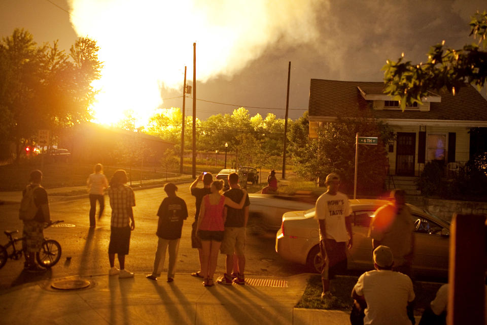 People watch the flames shoot up from a freight train that derailed and some cars burst into flames, early Wednesday morning July 11, 2012 in Columbus Ohio. Lt. Terry Bush says the accident happened at about 2 a.m. Wednesday in a mixed-use part of the city, and people living in one-mile radius of the blast have been evacuated. (AP Photo/Andrew Spear)