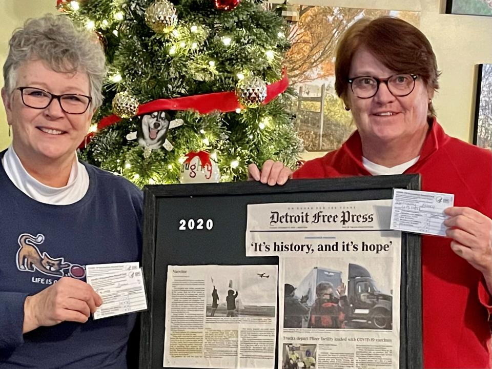 Susan Deur, left, and Nancy Galloway of Plainwell, Mich., hold up the newspaper clipping from the December 2020 day trucks filled with the nation's first doses of the Pfizer-BioNTech COVID-19 vaccine rolled out of the manufacturing plant in Portage, Mich.