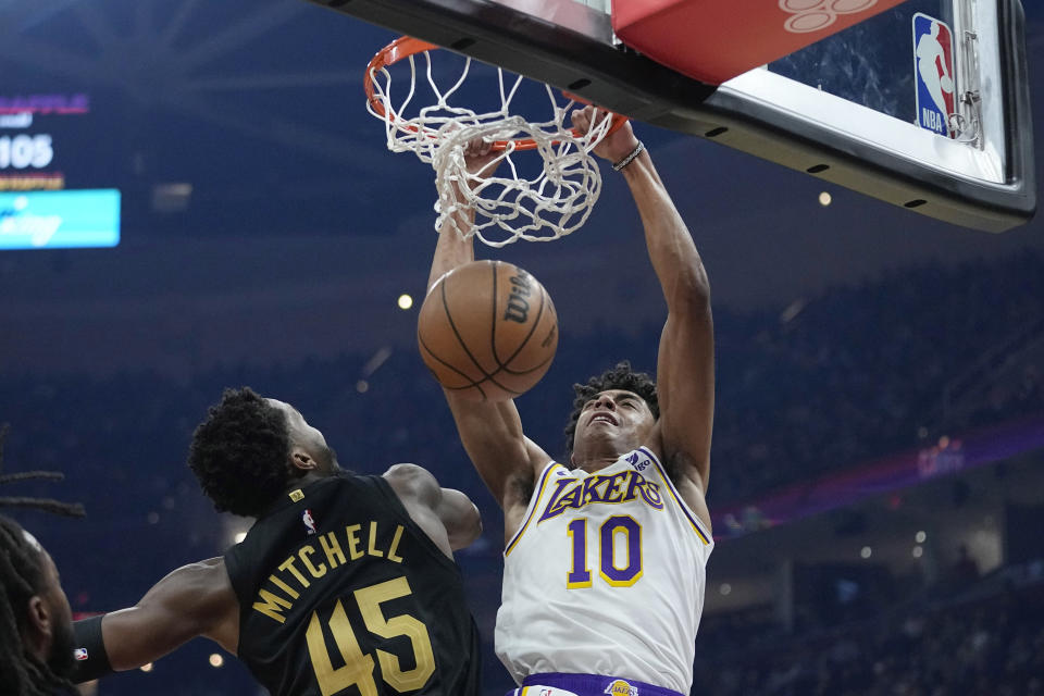 Los Angeles Lakers guard Max Christie (10) dunks over Cleveland Cavaliers guard Donovan Mitchell (45) during the first half of an NBA basketball game Saturday, Nov. 25, 2023, in Cleveland. (AP Photo/Sue Ogrocki)