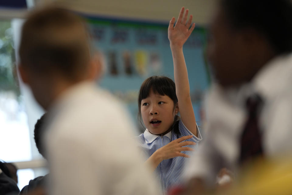 Isabella holds up her hand to answer a question in her year 4 class at the Holy Family Catholic Primary School in Greenwich, London, Wednesday, May 19, 2021. (AP Photo/Alastair Grant)