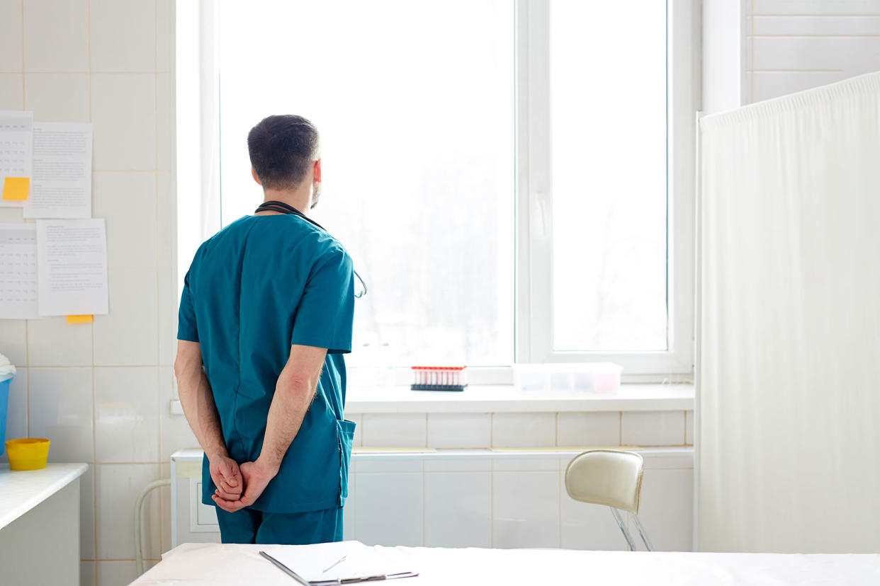 Doctor looking out window in a hospital Getty Images/shironosov