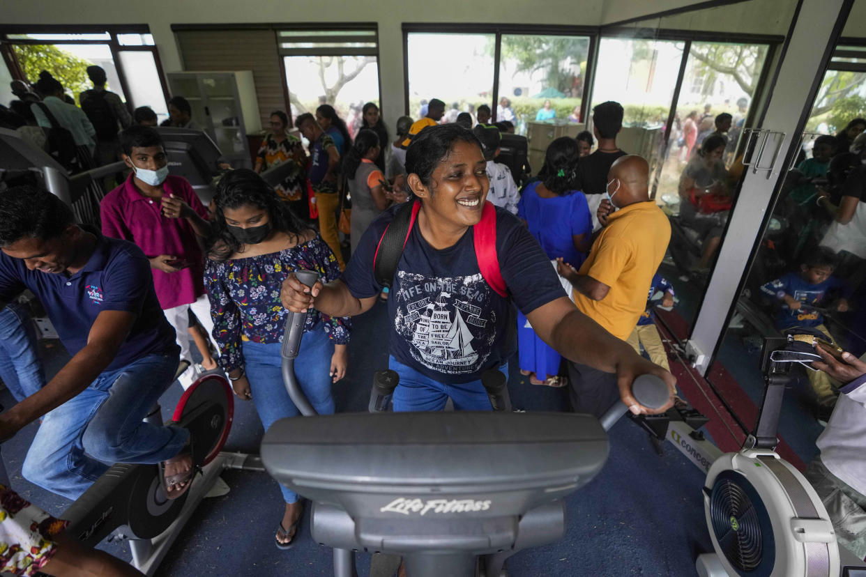 People use gym equipment as they throng President Gotabaya Rajapaksa's official residence on the second day after it was stormed in Colombo, Sri Lanka, Monday, July 11, 2022. Sri Lanka is in a political vacuum for a second day Monday with opposition leaders yet to agree on who should replace its roundly rejected leaders, whose residences are occupied by protesters, angry over the country's economic woes.(AP Photo/Eranga Jayawardena)