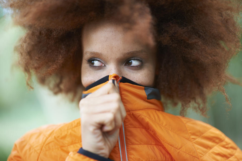 Close-up of a woman covering her mouth with her jacket collar