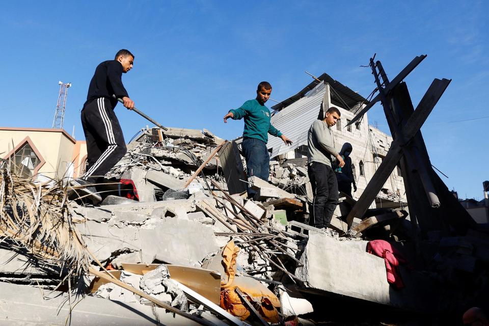 Varias personas sobre las ruinas de una casa.