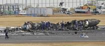 Firefighters gather around the burn-out Japanese coast guard aircraft at Haneda airport on Wednesday, Jan. 3, 2024, in Tokyo, Japan. Transport officials and police each began their on site investigation at Tokyo’s Haneda Airport on Wednesday after a large passenger plane and the Japanese coast guard aircraft collided on the runway and burst into flames, killing several people aboard the coast guard plane. (Kyodo News via AP)