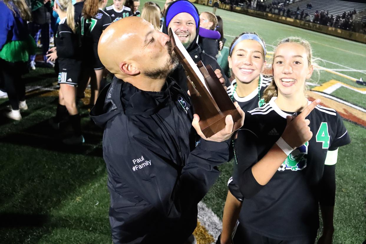 Longtime Colchester coach Jeff Paul kisses the state championship trophy after his Lakers defeated Essex in the 2023 Division I girls soccer ti title game.