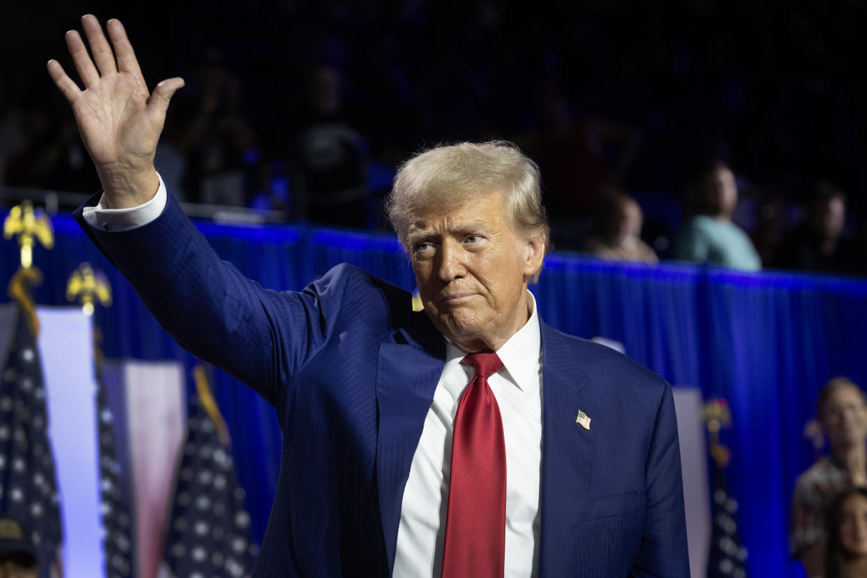  Donald Trump, wearing a blue suit with a red tie, waves and greets supporters following a recent town hall campaign event.