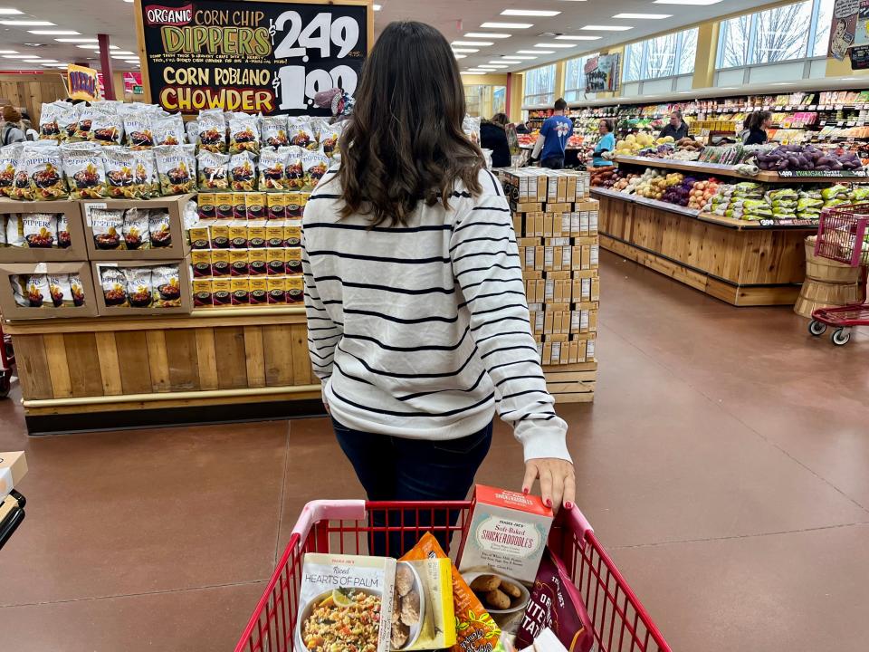 The writer leads a shopping cart full of items at Trader Joe's