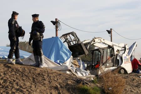 French CRS riot police secure the area as a bulldozer tears down makeshift shelters during the dismantlement of the camp called the "Jungle" in Calais, France, October 27, 2016. REUTERS/Pascal Rossignol