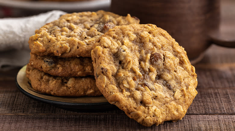 Oatmeal raisin cookies stacked before mug