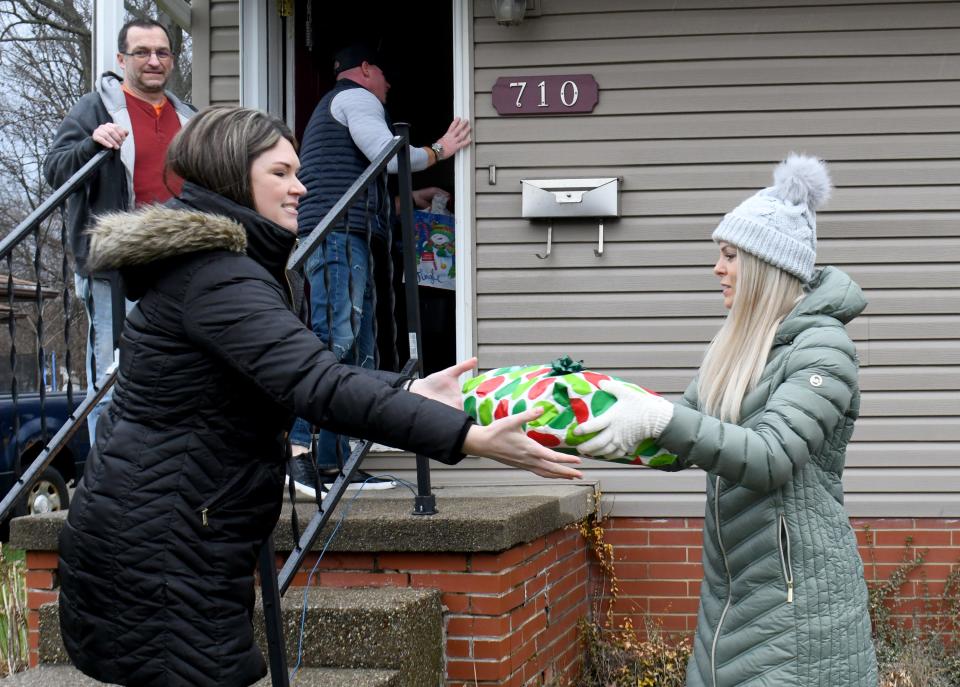 Volunteers pass Christmas gifts from a new vehicle to the Buzzelli Family's home in Alliance on Saturday, Dec. 23, 2023, as part of an annual giveaway from Sally & Assoc. Auto Sales, Inc., in Alliance.