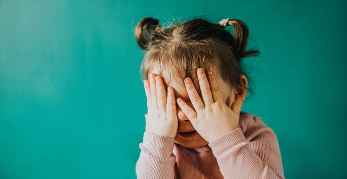 A little girl covering her face