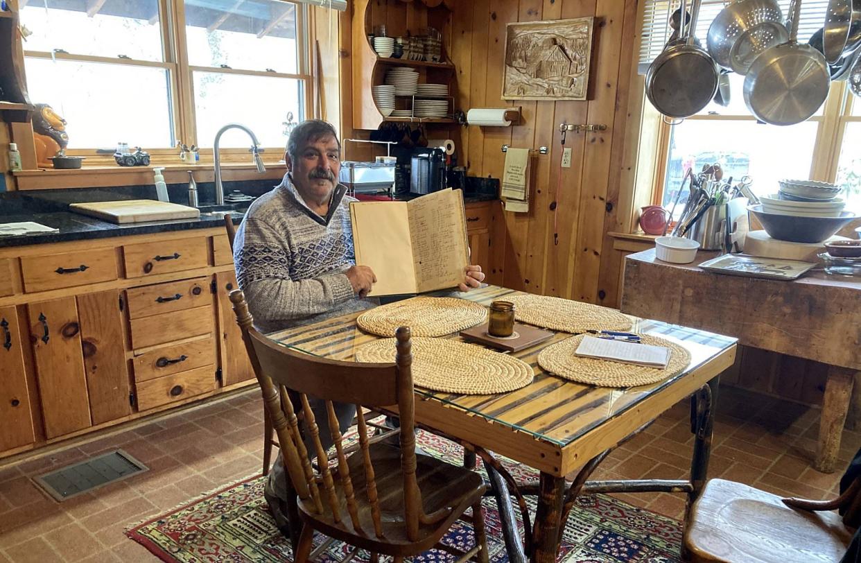 Ben Fisco holds a book that lists all the building materials, costs and people involved building the log house he owns at 10440 Route 6N in Albion. Fisco is selling the house, which was built in 1950.