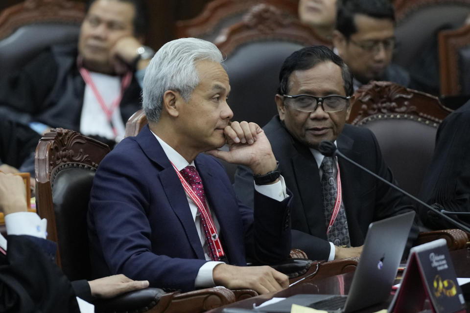 Presidential candidate Ganjar Pranowo, left, and his running mate Mahfud MD confer during their election appeal hearing at the Constitutional Court in Jakarta, Indonesia, Monday, April 22, 2024. The country's top court on Monday rejected appeals lodged by two losing presidential candidates who are demanding a revote, alleging widespread irregularities and fraud at the February polls. (AP Photo/Dita Alangkara)
