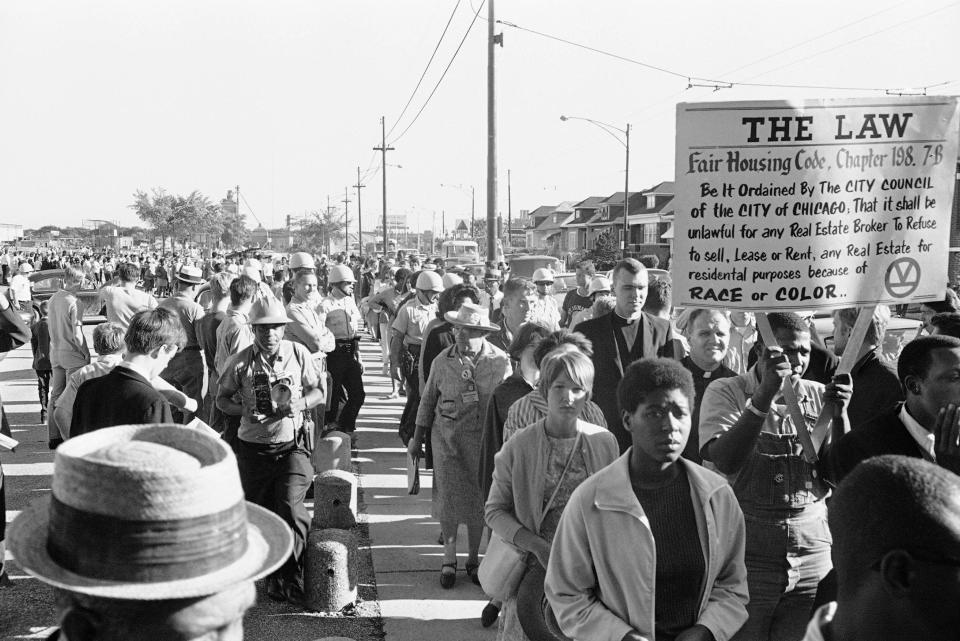 Police guard about 350 civil rights marchers as they trek through an all-white neighborhood in Chicago on Aug. 2, 1966. Some residents jeered and threw objects at the demonstrators protesting alleged housing discrimination by real estate dealers.