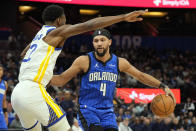 Golden State Warriors forward Andrew Wiggins, left, blocks the path of Orlando Magic guard Jalen Suggs to the basket during the first half of an NBA basketball game Wednesday, March 27, 2024, in Orlando, Fla. (AP Photo/John Raoux)