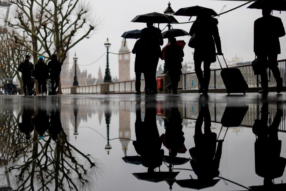 People walk past a puddle as they walk along the Southbank in the rain (EPA)