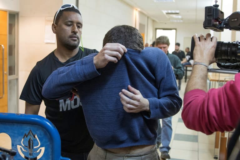 A US-Israeli Jewish teenager accused of making dozens of anti-Semitic bomb threats in the United States and elsewhere is escorted by guards as he leaves an Israeli court after his arrest