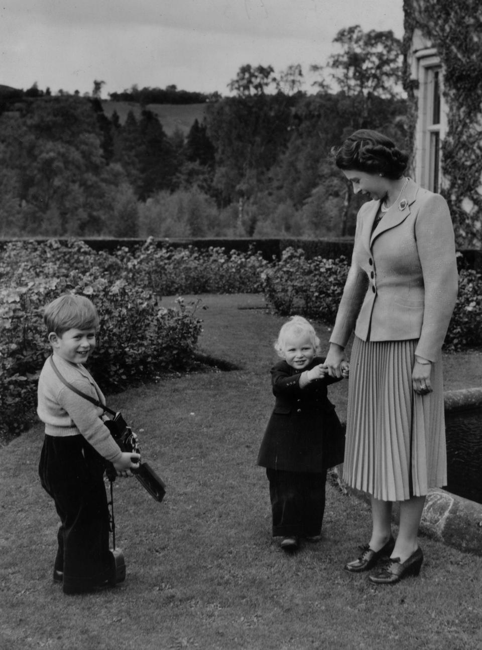 Queen Elizabeth II plays with her children Charles and Anne at Balmoral Castle