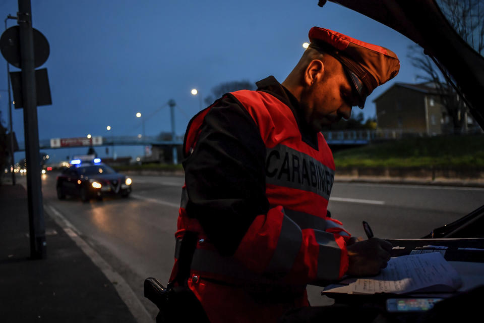 A policeman checks cars entering Milan, Northern Italy, Tuesday, March 10, 2020. People moving from one place to another must certificate they are doing it for work or important personal or health reasons, following the latest measures to slow down the diffusion of the new Coronavirus. For most people, the new coronavirus causes only mild or moderate symptoms, such as fever and cough. For some, especially older adults and people with existing health problems, it can cause more severe illness, including pneumonia. (Claudio Furlan/LaPresse via AP)