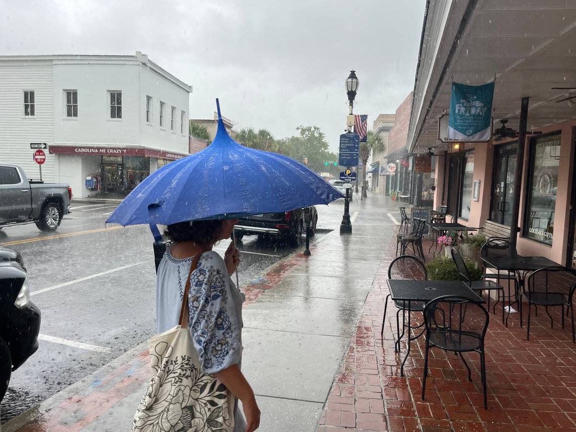 Alex Kosarko of Charleston makes her way down Bay Street Monday morning, shielding herself with an umbrella as she walked in Downtown Beaufort, South Carolina, on Monday, Aug. 5, 2024. “We’re from Charleston so we’re used to it,” Kosarko said as a deluge of rain came.