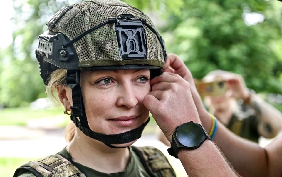 A servicewoman of the 128th Mountain Assault Brigade gets help putting on a helmet before Ukraine's largest annual sports and charity event in the Zaporizhzhia Region, southeastern Ukraine. - Ukrinform/Shutterstock/Shutterstock