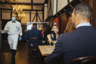 Wax statues of Audrey Hepburn and Michael Strahan occupy one of the tables at Peter Luger Steakhouse on Friday, Feb, 26, 2021, in New York. Five statues, on loan from Madame Tussauds, will occupy unused tables during COVID-19 occupancy restrictions. (AP Photo/Kevin Hagen)