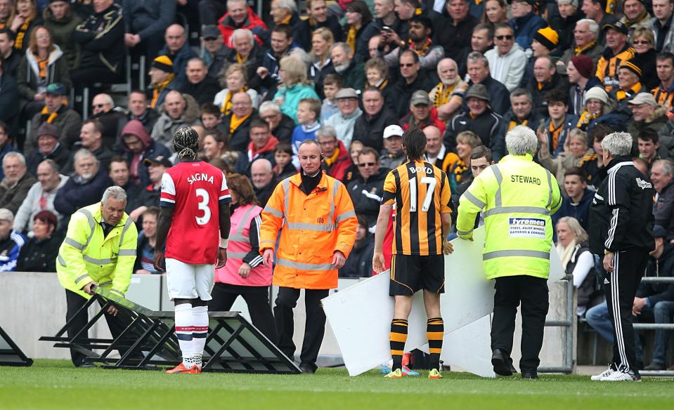 Players and stewards help replace the advertising boards after they were blown onto the pitch during the English Premier League match Hull City against Arsenal at The KC Stadium, Hull, England, Sunday April 20, 2014. (AP Photo/PA, Lynne Cameron) UNITED KINGDOM OUT NO SALES NO ARCHIVE
