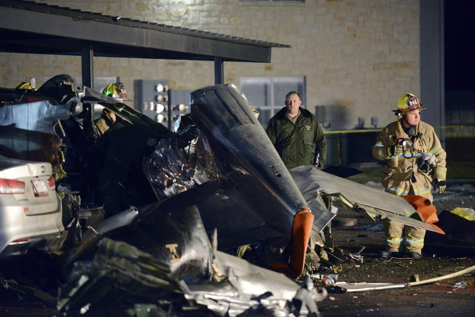 FILE - In this Nov. 17, 2018, file photo, firefighters and investigators look over a vintage World War II P-51D Mustang aircraft after a deadly crash in Fredericksburg, Texas. The fatal crash in Connecticut of a World War II B-17 bomber on Wednesday, Oct. 2, 2019, was the latest in a long list of fatal crashes involving vintage planes used or designed for military purposes. (Billy Calzada/The San Antonio Express-News via AP, File)