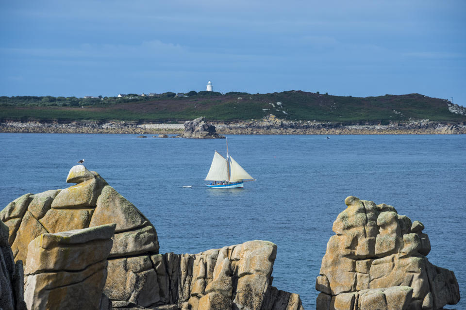 UK, England, Isles of Scilly, St. Mary's, Sailing boat behind huge granite rocks