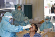 A health worker takes a swab test at a COVID-19 testing center in New Delhi, India, Monday, April 27, 2020. India’s main medical research organization has cancelled orders to procure rapid antibody test kits from two Chinese companies after quality issues and controversies over its price. (AP Photo/Manish Swarup)