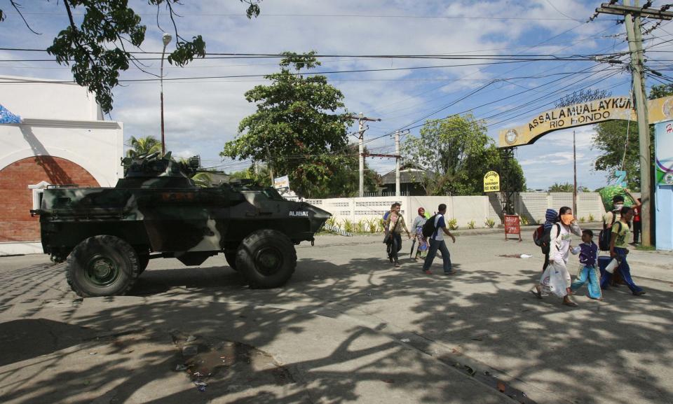 Residents walk past a government military vehicle as they evacuate near an area where members of Muslim rebels MNLF have occupied, in Zamboanga city