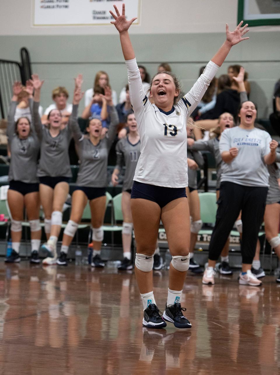 Savannah Browning (No. 13) and her Gulf Breeze teammates celebrate their victory over Catholic on Thursday, Sept. 29, 2022. The Dolphins defeated the Crusaders in three straight games, 25-16, 25-16, 25-17.