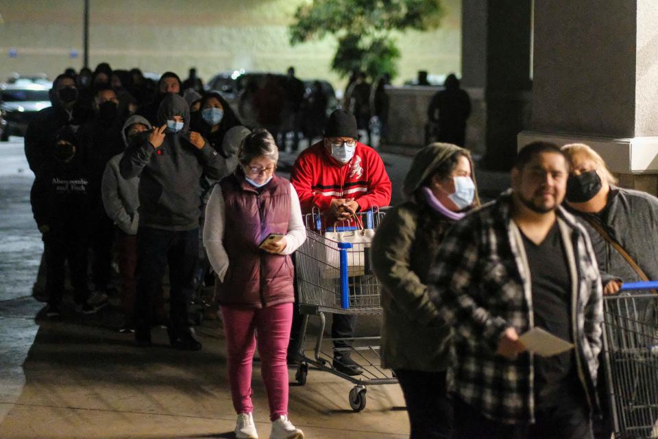 Black Friday shoppers wearing face masks wait in line to enter a Walmart store Pico Rivera Calif., Friday, Nov. 26, 2021.