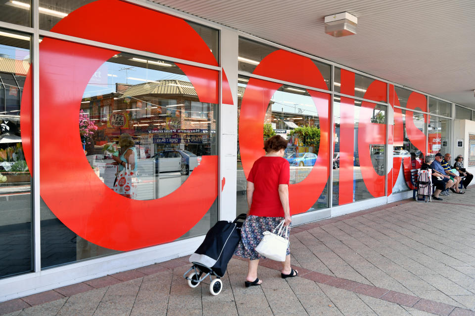 The front of a Coles store as customers walk past.