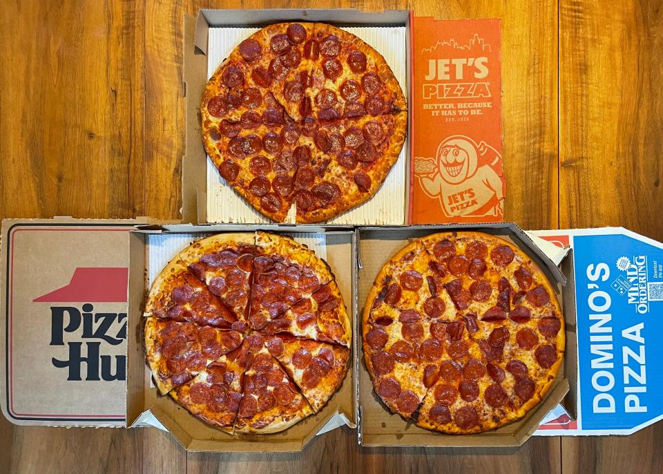 three pizzas - pizza hut, jets, and dominoes open on a table