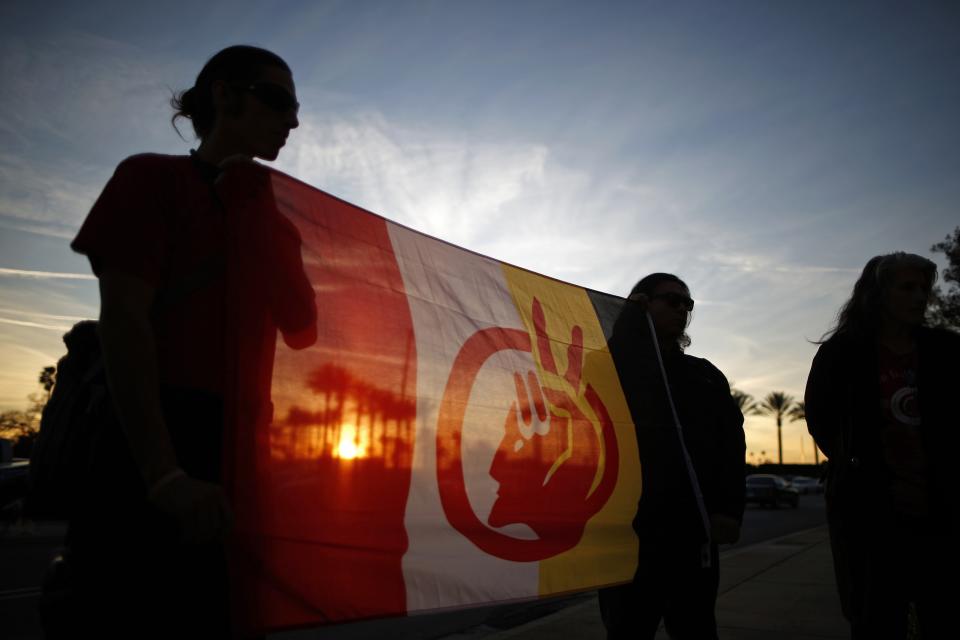 People holding the American Indian movement flag protest against the Keystone XL Pipeline, which would carry petroleum from Canada to refineries in Texas, outside WorleyParsons engineering consultancy company in Arcadia, California January 14, 2015. The U.S. Senate advanced a bill on Monday to approve the pipeline as Republicans, who have made the project their first priority of the year, try to line up enough votes to overcome a potential veto by President Barack Obama. REUTERS/Lucy Nicholson (UNITED STATES - Tags: ENVIRONMENT CIVIL UNREST ENERGY BUSINESS SOCIETY)