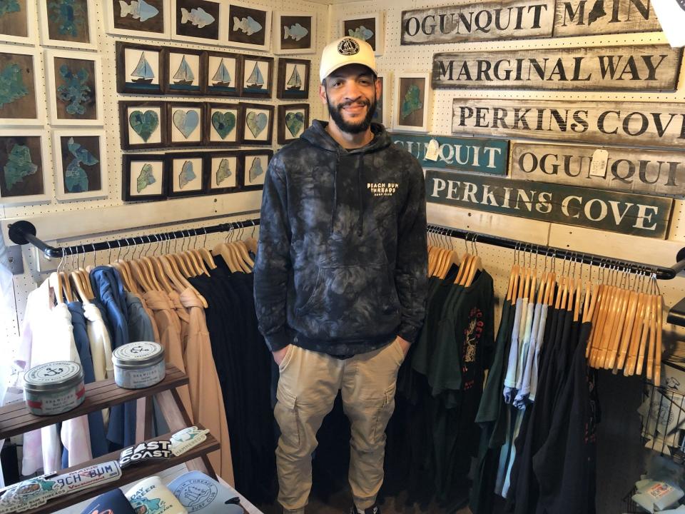 Employee Mike Moats is a jack of all trades at Beach Bum Threads, a new shop at 116 Perkins Cove Road in Ogunquit, Maine. He is seen here among local artwork and other items that the shop sells.