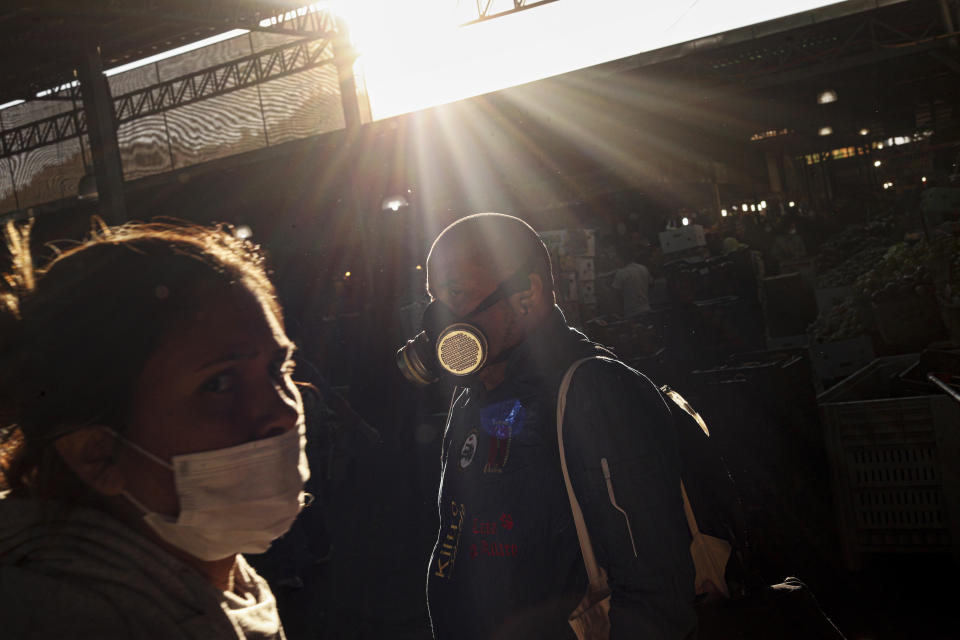 People wearing protective masks walk through La Vega market in Santiago, Chile, March 24, 2020. (AP Photo/Esteban Felix)