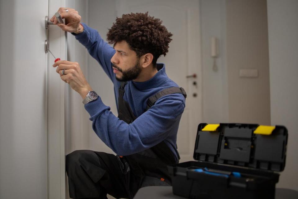 A man uses a tool to fix a lock. 