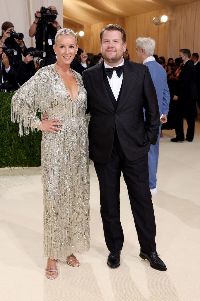 Julia Carey wears a long sparkly long sleeve gown with fringe and James Corden wears a dark suit