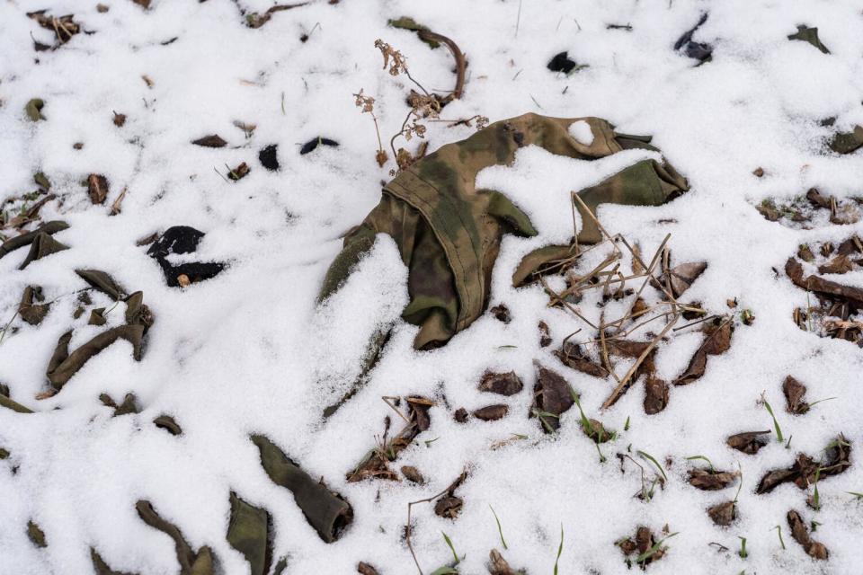 A fragment of Russian fatigues pokes out from under a dusting of snow in a village park in Bilyayivka.