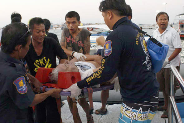 Thai rescuers carry an injured tourist on to the pier after being rescued from the sea after a boat accident in Pattaya, southeastern Thailand Sunday, Nov. 3, 2013. Six tourists, including two Russians and a Chinese, were killed when an overcrowded ferry sank, police said. (AP Photo/Daily News) THAILAND OUT