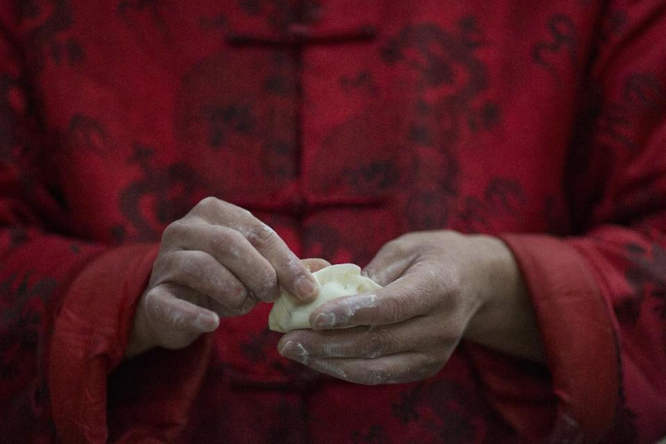 Un hombre da forma a una empanadilla durante una reunión local antes de los festejos del Año Nuevo lunar en un pueblo a las afueras de Beijing, China, el jueves 26 de enero de 2017. (AP Foto/Ng Han Guan)