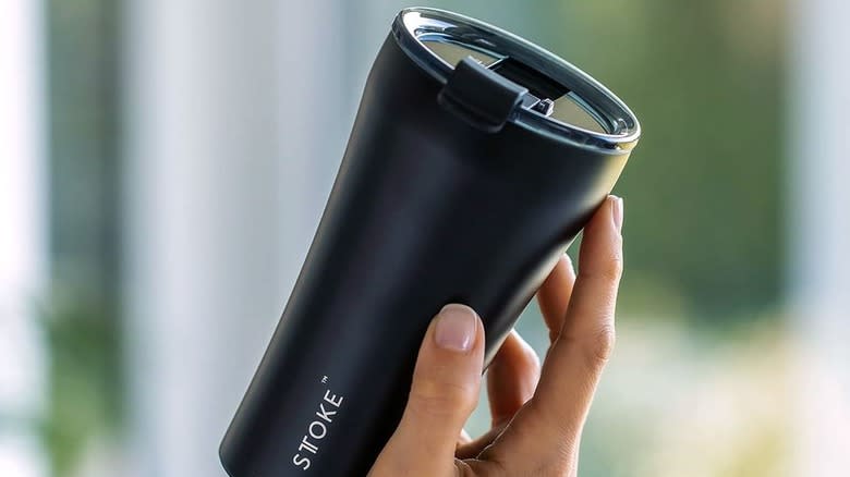 hand holding black insulated tumbler