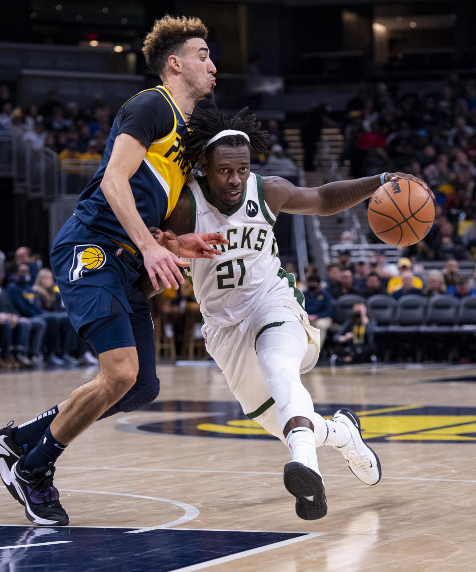 Milwaukee Bucks guard Jrue Holiday (21) drives the ball into the defense of Indiana Pacers guard Chris Duarte (3) during the second half of an NBA basketball game in Indianapolis, Sunday, Nov. 28, 2021. (AP Photo/Doug McSchooler)