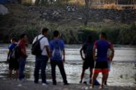 Migrants travelling to the U.S. gather by the Suchiate river as they are watched by members of the mexican National guard, at the border between Guatemala and Mexico, in Tecun Uman